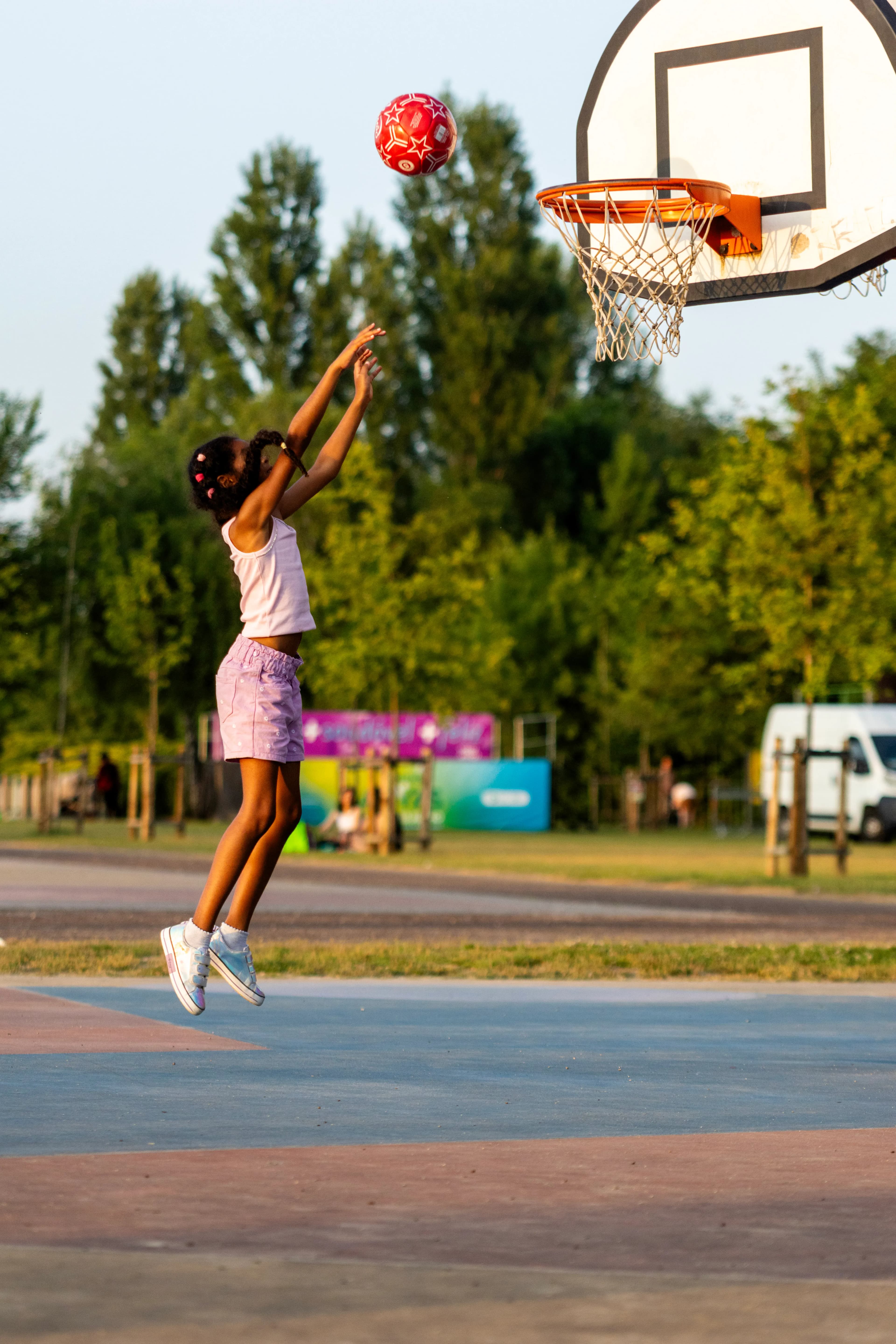 Jeune fille qui saute pour marquer un panier de basket en plein air